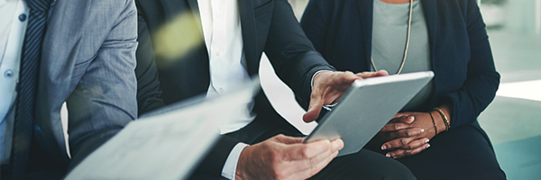 Businessman holding a tablet and explaining what's on the screen to his colleagues.