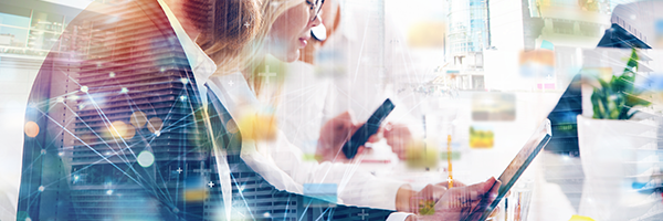 Businesswoman leaning over a table and working on a tablet.