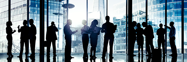 Businessmen and businesswomen standing in the lobby of a building and collaborating with each other.