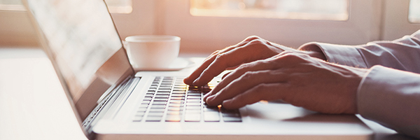 Closeup of hands typing on a laptop keyboard.