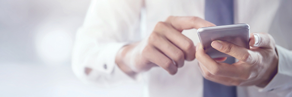 Businessman standing and typing on his smartphone.